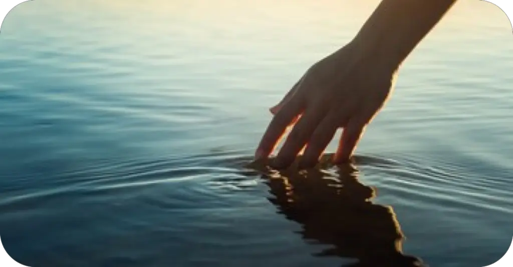 Hand touching water representing calm, simplicity, and an easy first step into mindful reflection.