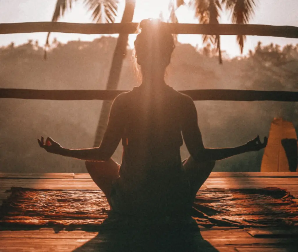 Person meditating outdoors representing happiness, calm, and mindful practice.