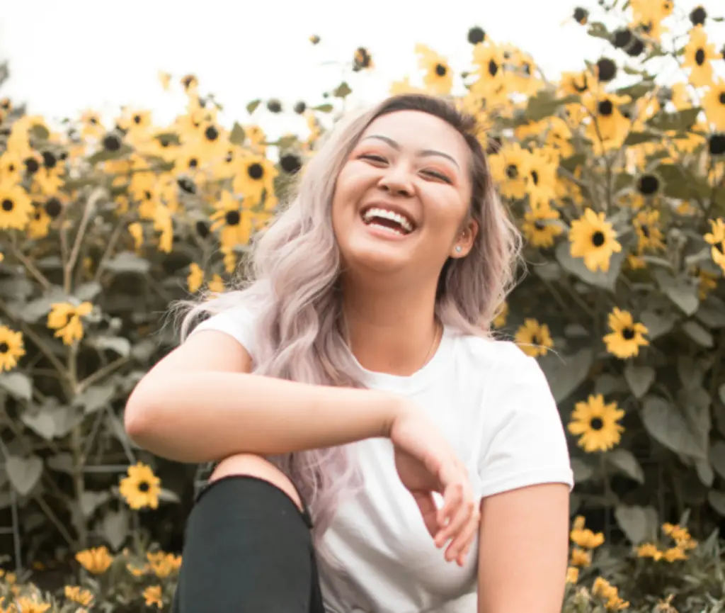 Person smiling in a sunflower field representing mindfulness, happiness, and everyday reflection.